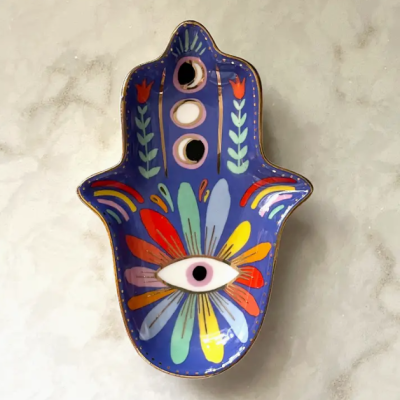 Prato decorativo em forma de mão com pintura colorida e olho estilizado.