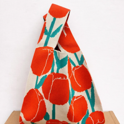 Mala de tecido com padrão floral laranja e verde em fundo bege