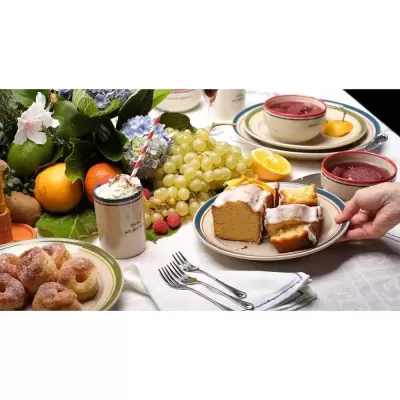 Mesa com sobremesas incluindo bolo com cobertura, roscas, tigela LAUF, copo com chantilly e frutas frescas
