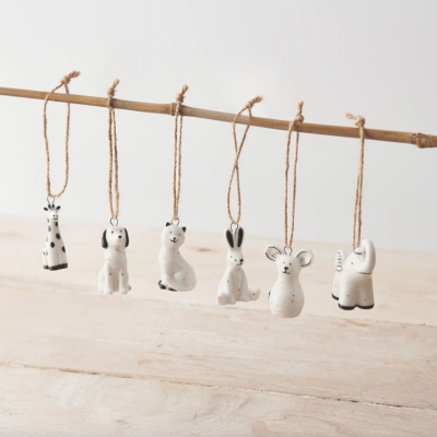Seis figuras de animais penduradas em cordas de juta sobre um ramo, fundo branco e piso de madeira