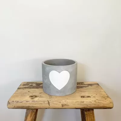 Vaso de cimento cinzento com coração branco em banco de madeira rústica