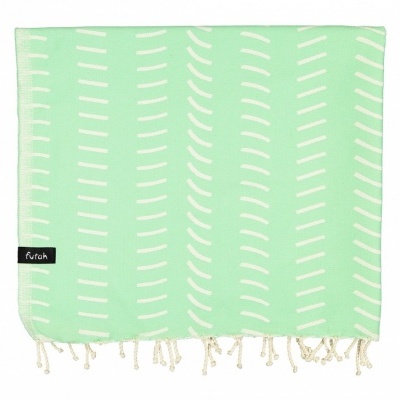 Toalha ou manta verde claro com padrão branco e franjas, etiqueta preta com texto