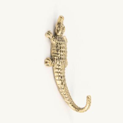 Gancho de parede dourado em forma de crocodilo sobre fundo branco