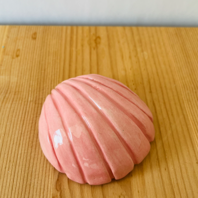 Produto cerâmico rosa em forma de concha sobre superfície de madeira