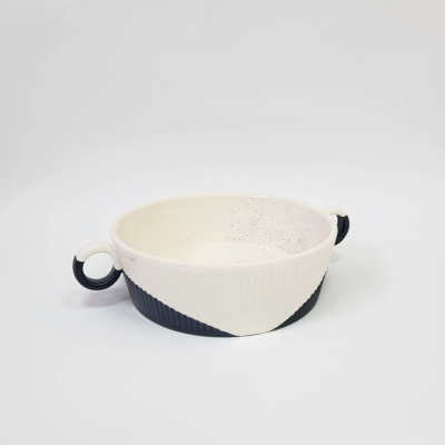 Taça redonda de cerâmica branca e preta com pegas circulares.