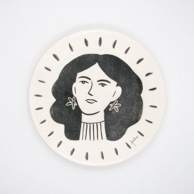 Prato redondo branco com ilustração em preto da cabeça de uma mulher