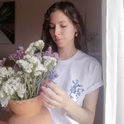 Mulher com camiseta branca a segurar vaso de flores em ambiente iluminado naturalmente