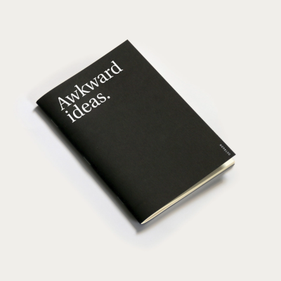 Caderno preto com texto branco Awkward ideas.