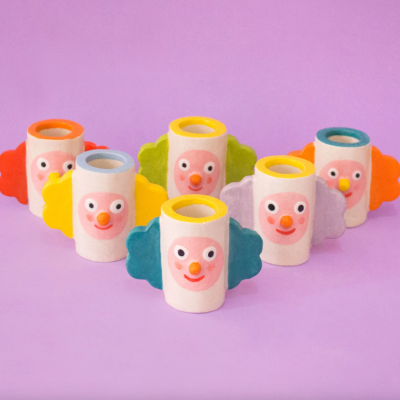 Vasos decorativos com rosto sorridente colorido sobre fundo lilás