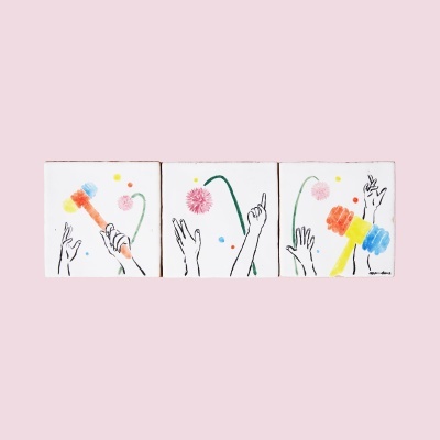 Três quadros com desenhos de mãos e martelos coloridos sobre fundo branco e parede rosa