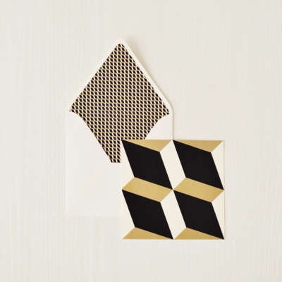 Cartão quadrado com padrão geométrico preto, branco e dourado e envelope branco com interior estampado