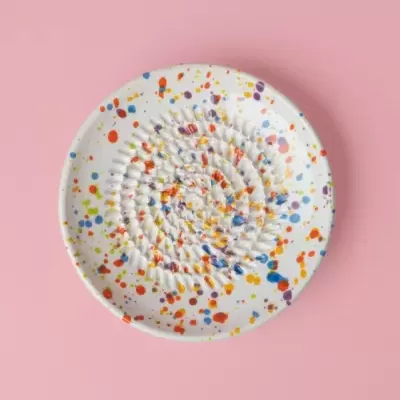 Prato cerâmico branco com manchas coloridas e textura ondulada no centro