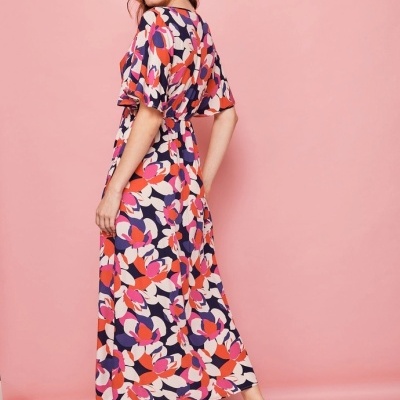 Vestido longo feminino floral colorido com sandálias castanhas em fundo rosa