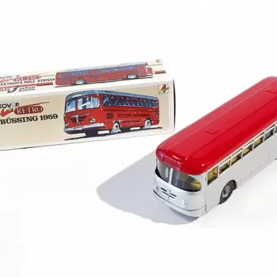 Modelo de autocarro de brinquedo metálico branco com vermelho à frente da caixa original.