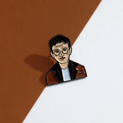 Pin esmaltado de pessoa com óculos e casaco castanho sobre fundo castanho e branco