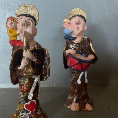 Duas figuras decorativas de cerâmica pintadas com adultos e crianças e instrumentos musicais.