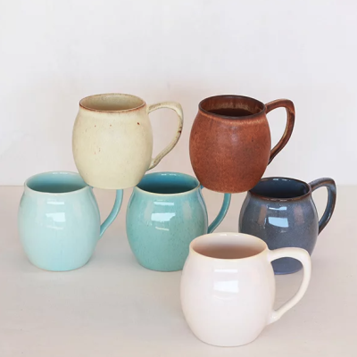 Conjunto de canecas de cerâmica coloridas em fundo branco.