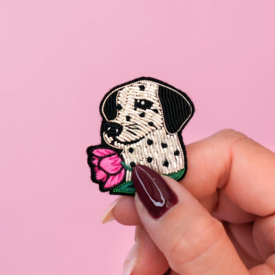 Patch bordado de dálmata segurando flor rosa sobre fundo rosa