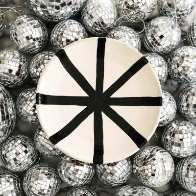 Prato branco com padrão preto cercado por bolas de espelho prateadas