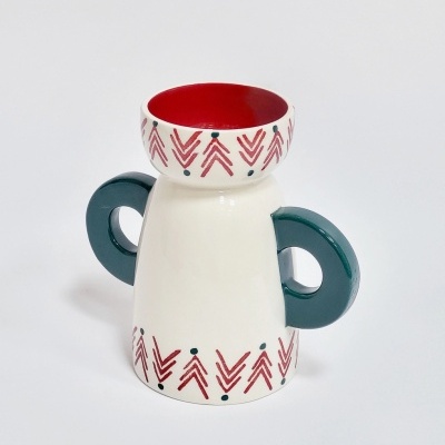 vaso cerâmico branco com pegues verdes e padrões geométricos vermelhos