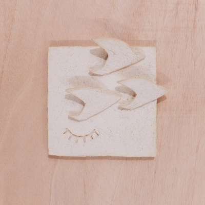 Escultura decorativa de parede com pássaros em cerâmica branca sobre madeira clara