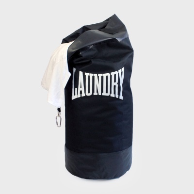 Saco preto de lavanderia com a palavra LAUNDRY a branco e roupa branca pendurada