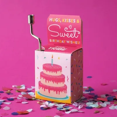 Caixa de música com ilustração de bolo de aniversário e texto comemorativo, com manivela metálica.