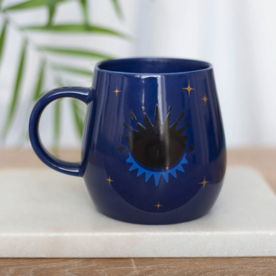 Caneca azul escura com desenho de olho e estrelas douradas
