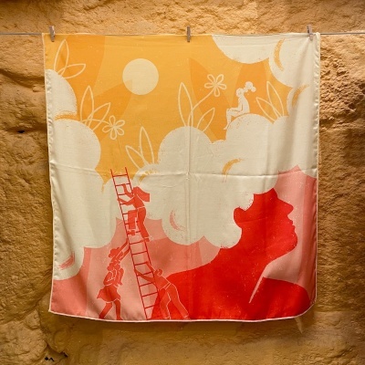 Pano de tecido com padrão artístico colorido pendurado numa parede de pedra.