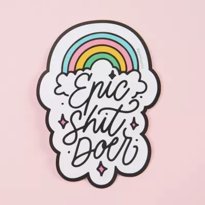 Adesivo com arco-íris e texto 'Epic shit doer' em fundo branco e rosa.