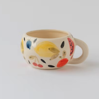 Caneca de cerâmica branca com desenhos de frutas coloridas