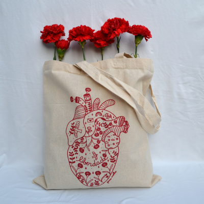 Saco de tecido bege com impressão vermelha de coração anatómico e cravos vermelhos.