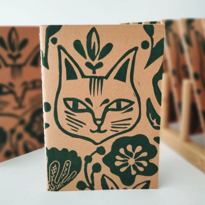 Caixa de cartão castanho decorada com desenho verde de cara de gato e flores