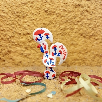 Estatueta de galo pintada com flores e a palavra freedom