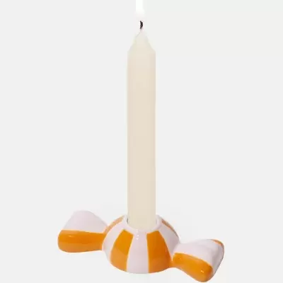 Castiçal em cerâmica laranja e branco com vela acesa