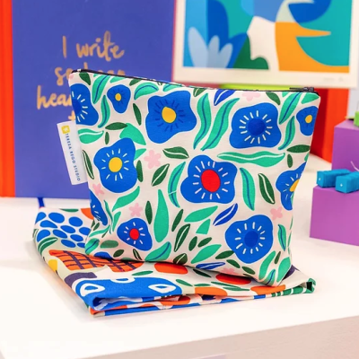 Estojo floral azul, vermelho e verde com etiqueta Olli Ella numa superfície branca