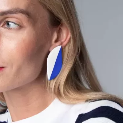 Brinco abstrato azul e branco no lóbulo da orelha de mulher com cabelo loiro