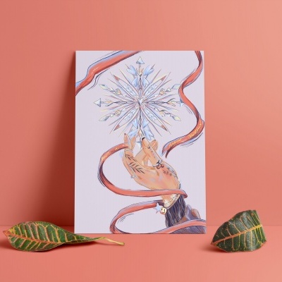 Cartão com ilustração em fundo coral, mão segurando cristal detalhado envolvido em linhas vermelhas, folhas verdes ao lado