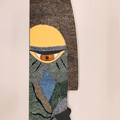 Máscara decorativa de parede com padrões coloridos pontilhados e rosto estilizado