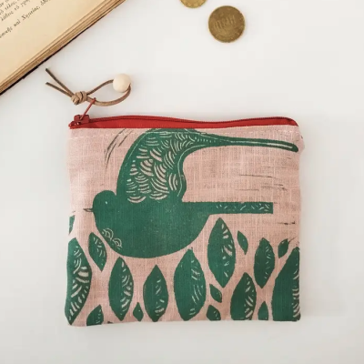 Carteira rosa com padrão verde de pássaro e folhas, fecho vermelho, cordão marrom e conta de madeira