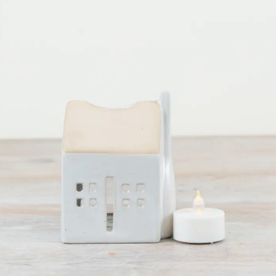 Casa decorativa branca em cerâmica com vela elétrica ao lado