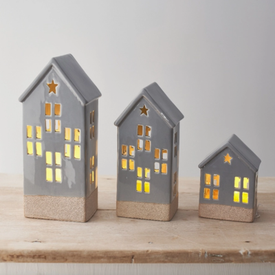 Três casas decorativas em cerâmica cinza com luzes amarelas