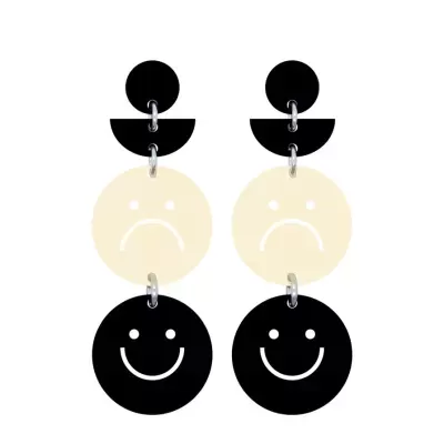 Brincos pretos e creme com rostos sorridentes e tristes em formatos circulares
