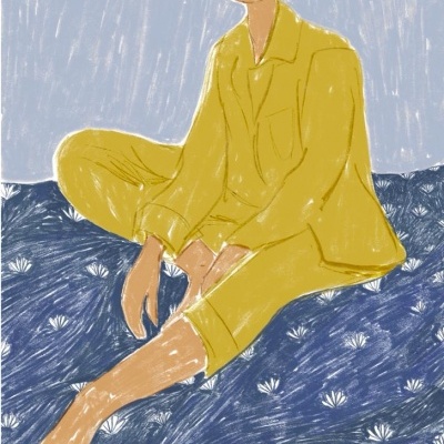 Pessoa sentada com pijama amarelo sobre superfície azul com padrão branco