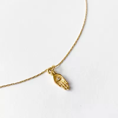Colar dourado com pendente em forma de mão hamsá e detalhe em cristal