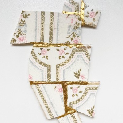 Fragmentos de cerâmica com padrão floral e linhas douradas reparados