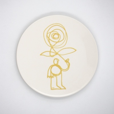 Prato branco com desenho amarelo de figura humana segurando rosa