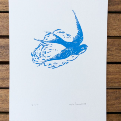 Gravura de pássaro azul a voar sobre papel branco, assinado e numerado, sobre madeira.