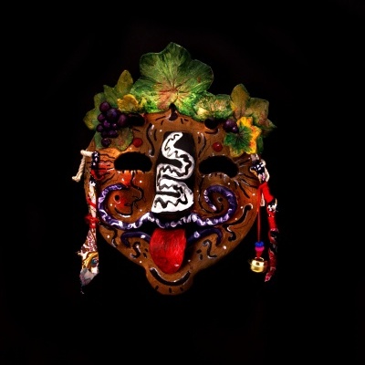 Máscara decorativa colorida com folhas, uvas e cordões em fundo preto