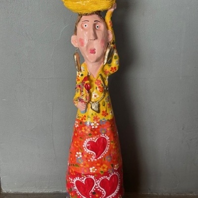 Estátua colorida de mulher com vestido e cesta com galinhas